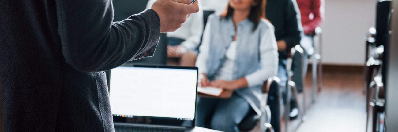 Everyone is smiling and listens. Group of people at business conference in modern classroom at daytime