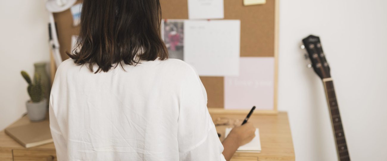 vista-posterior-mujer-escribiendo-en-un-cuaderno