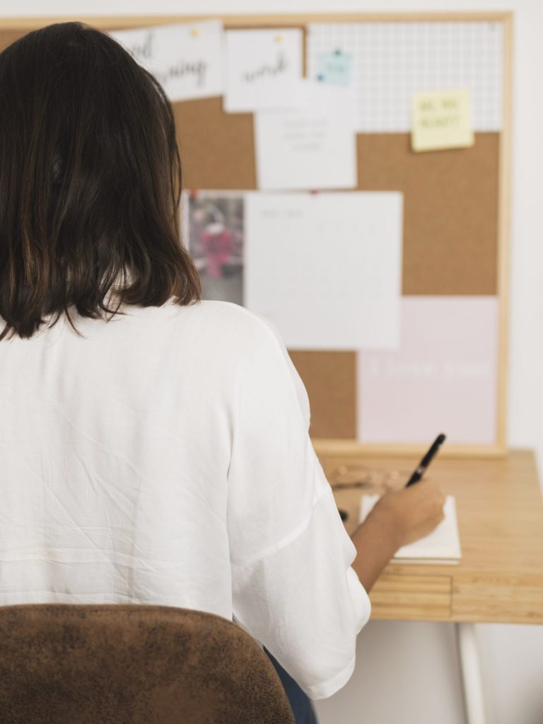 vista-posterior-mujer-escribiendo-en-un-cuaderno