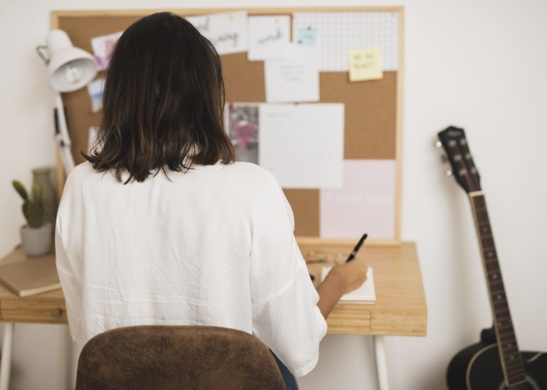 vista-posterior-mujer-escribiendo-en-un-cuaderno