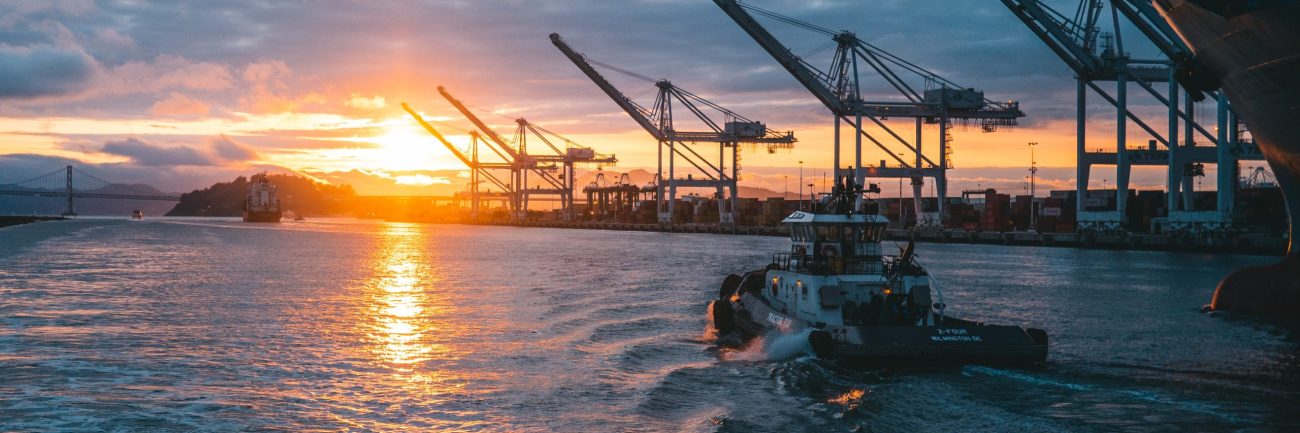 Panoramic shot of oil rigs at sea with a beautiful sunset in the background, under cloudy sky