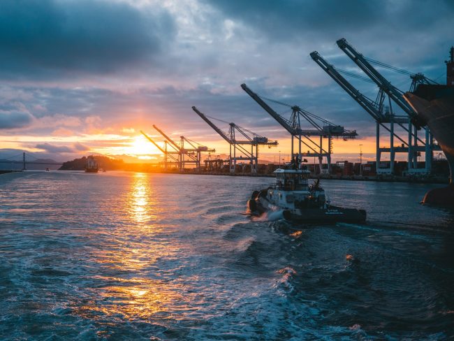 Panoramic shot of oil rigs at sea with a beautiful sunset in the background, under cloudy sky