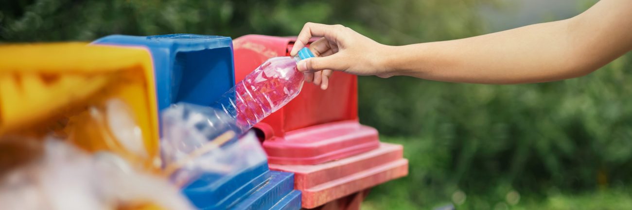 hand holding bottle plastic garbage into trash in park