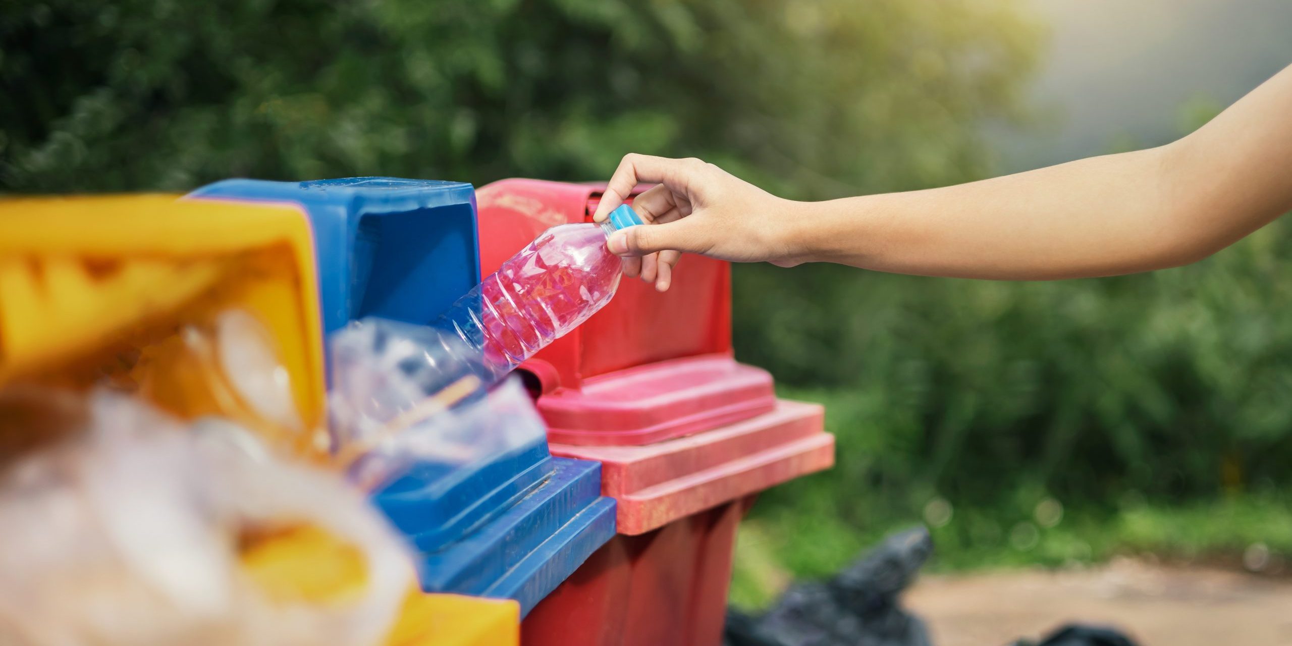 hand holding bottle plastic garbage into trash in park