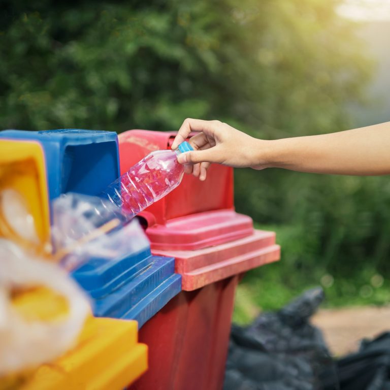 hand holding bottle plastic garbage into trash in park