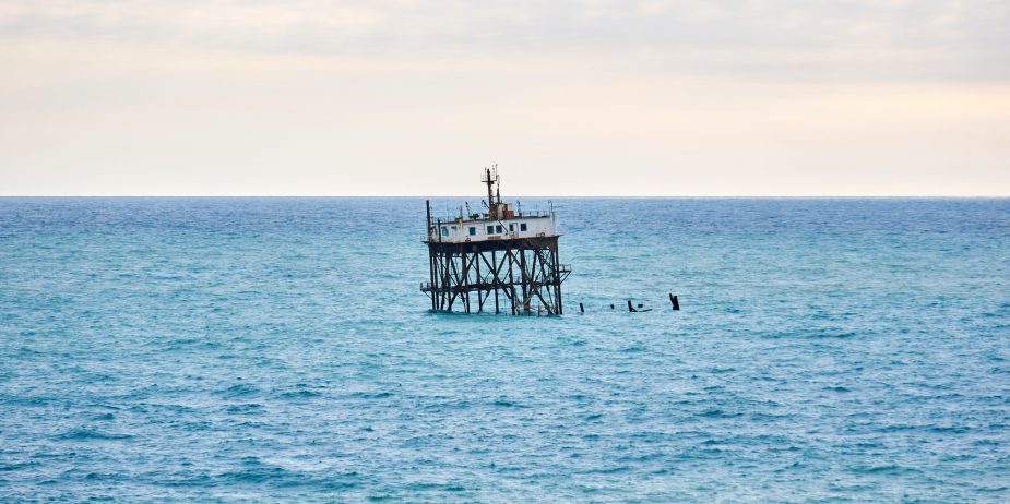seascape with a rickety structure on the stilts of an aquaculture farm