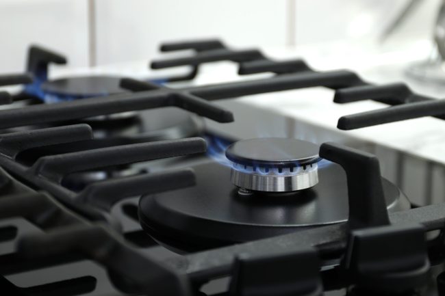 Closeup shot of blue fire from domestic kitchen stove top. Gas cooker with burning flames of propane gas. Industrial resources and economy concept.