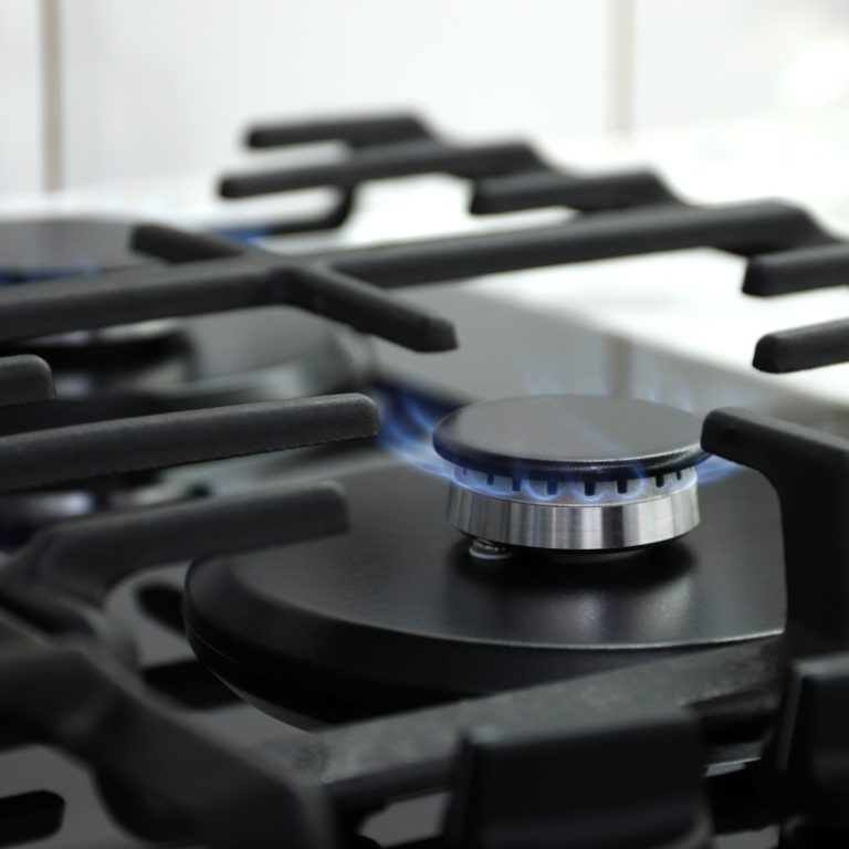 Closeup shot of blue fire from domestic kitchen stove top. Gas cooker with burning flames of propane gas. Industrial resources and economy concept.