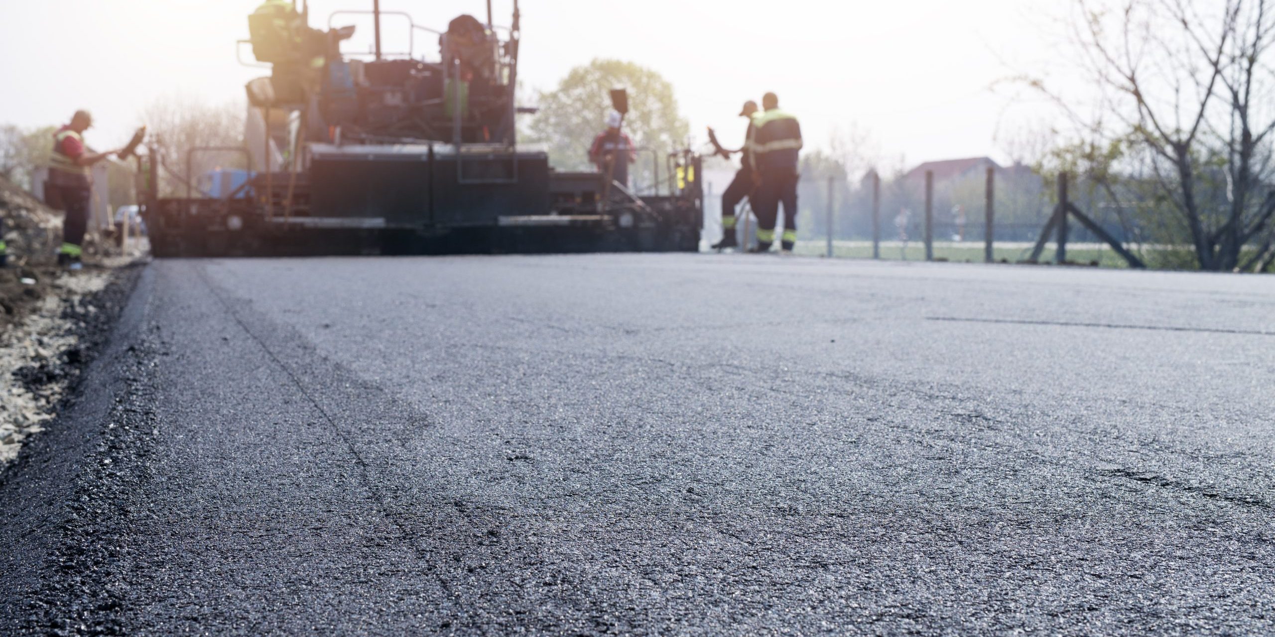 Workers placing new coating of asphalt on the road.