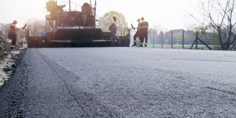 Workers placing new coating of asphalt on the road.