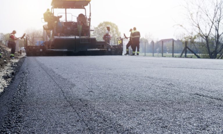 Workers placing new coating of asphalt on the road.