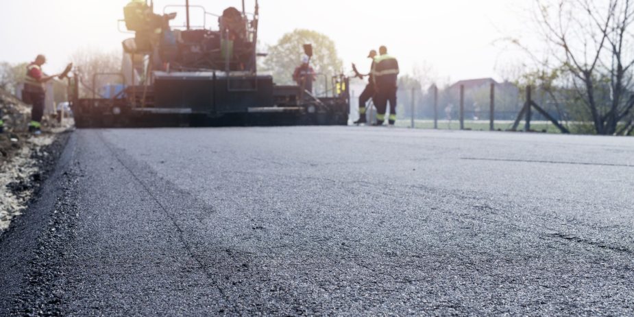 Workers placing new coating of asphalt on the road.