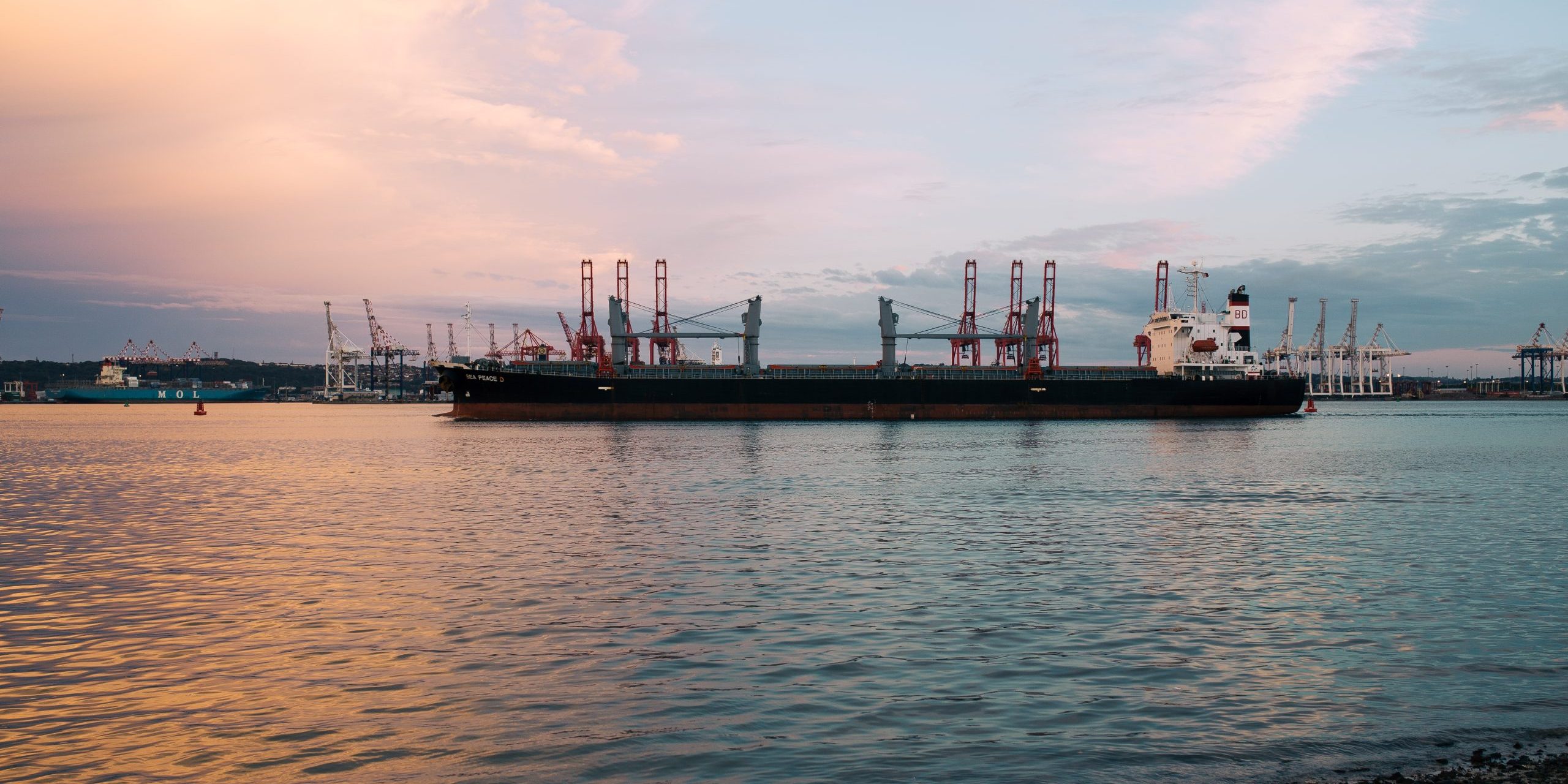 Cargo ship parked at the harbor on a sunny day during sunset