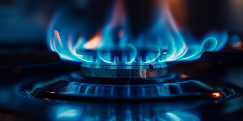 A close-up view of a gas stove burner with blue flames.